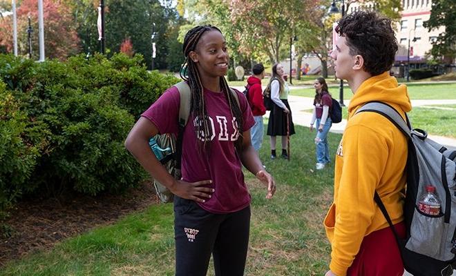 Students talking happily on the green, sunny campus